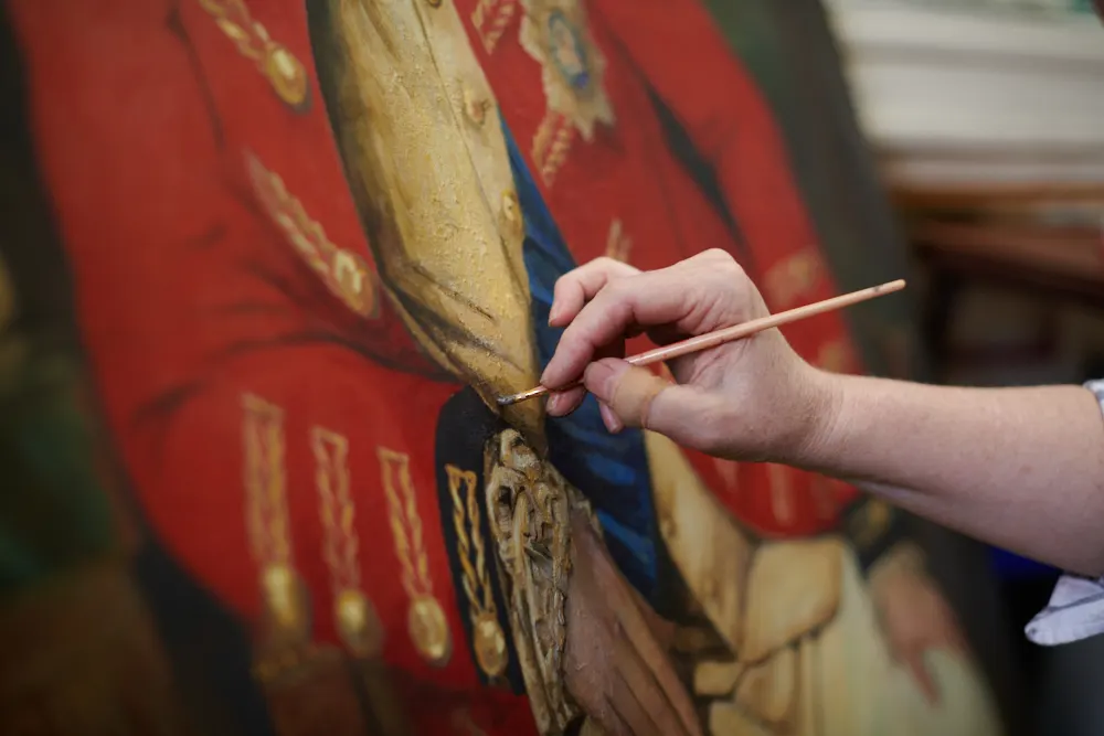 A conservator carefully treating a historic painting at Endangered Heritage